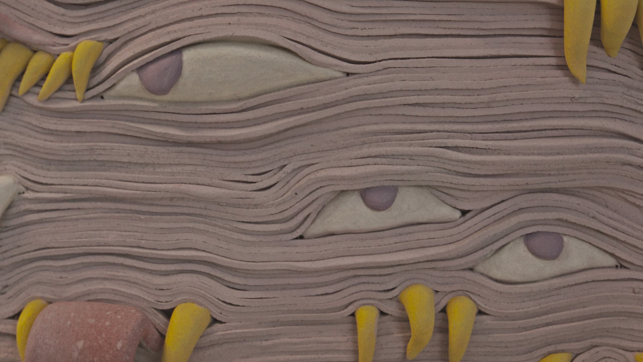 A clay relief of layered eyes and yellow claws