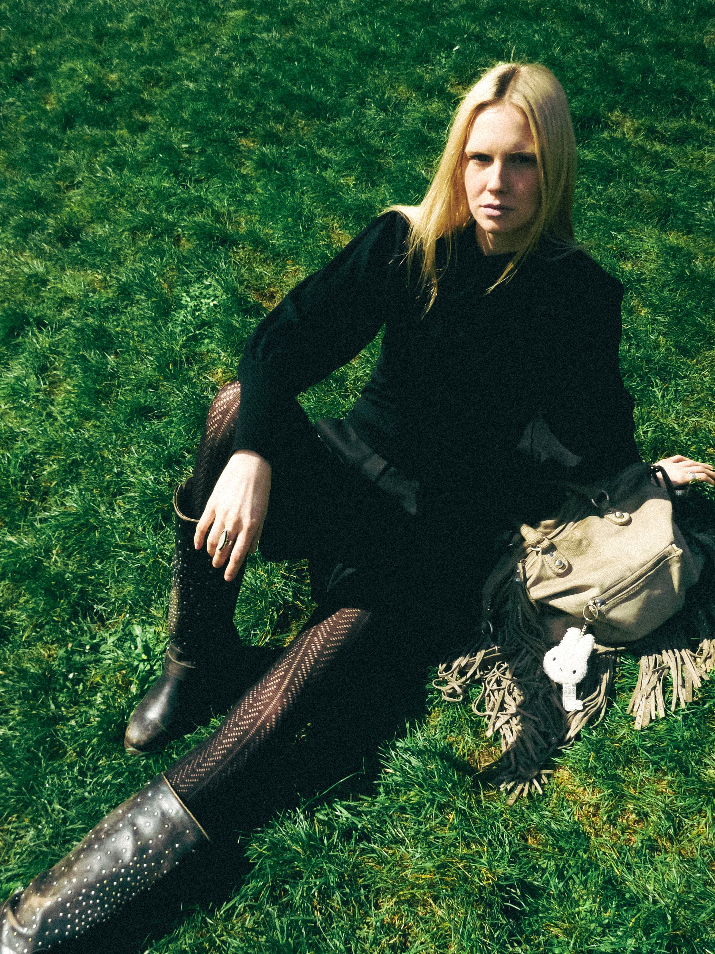Lea Pliger seated in the grass, a bag beside her