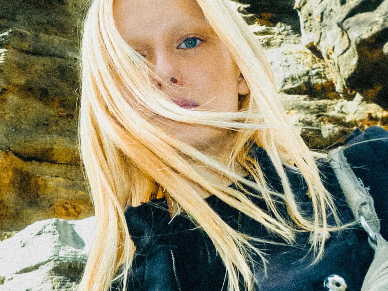 Lea Pliger, hair across her face, among rocks