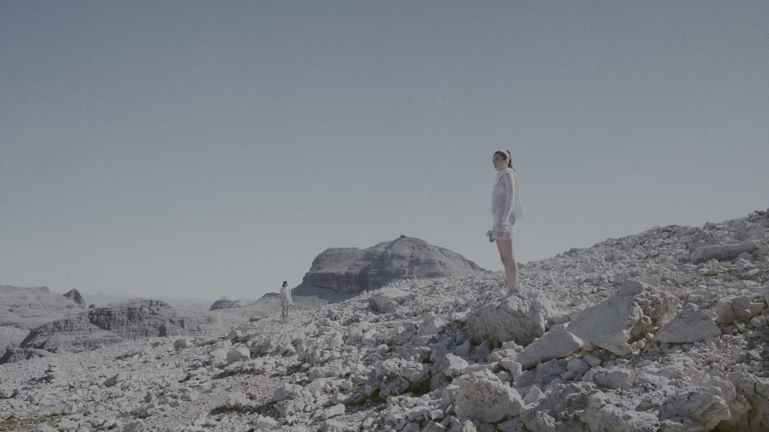 A figure standing on a rocky ridge at Passo Pordoi