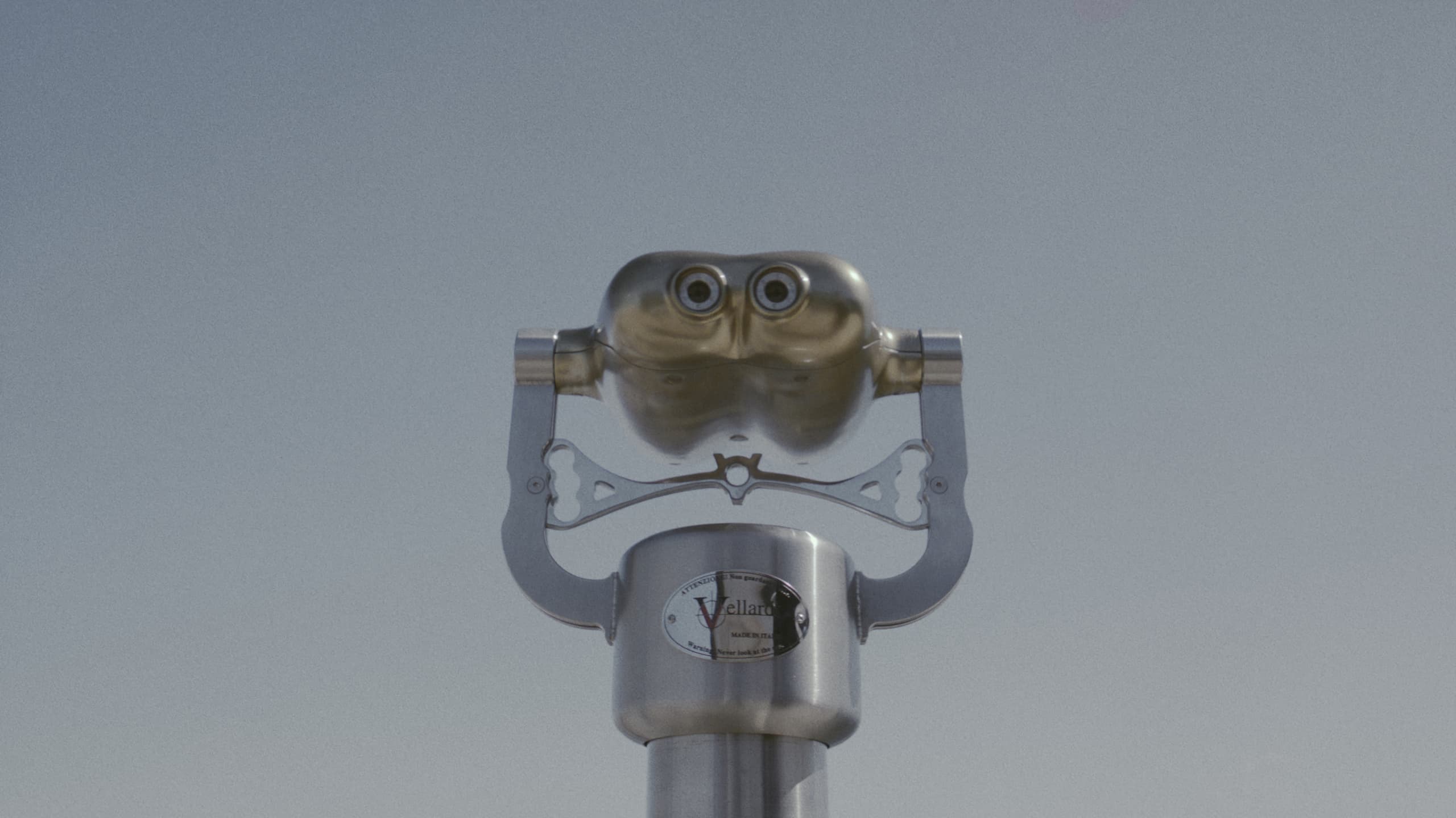 A coin-operated viewer against a pale sky